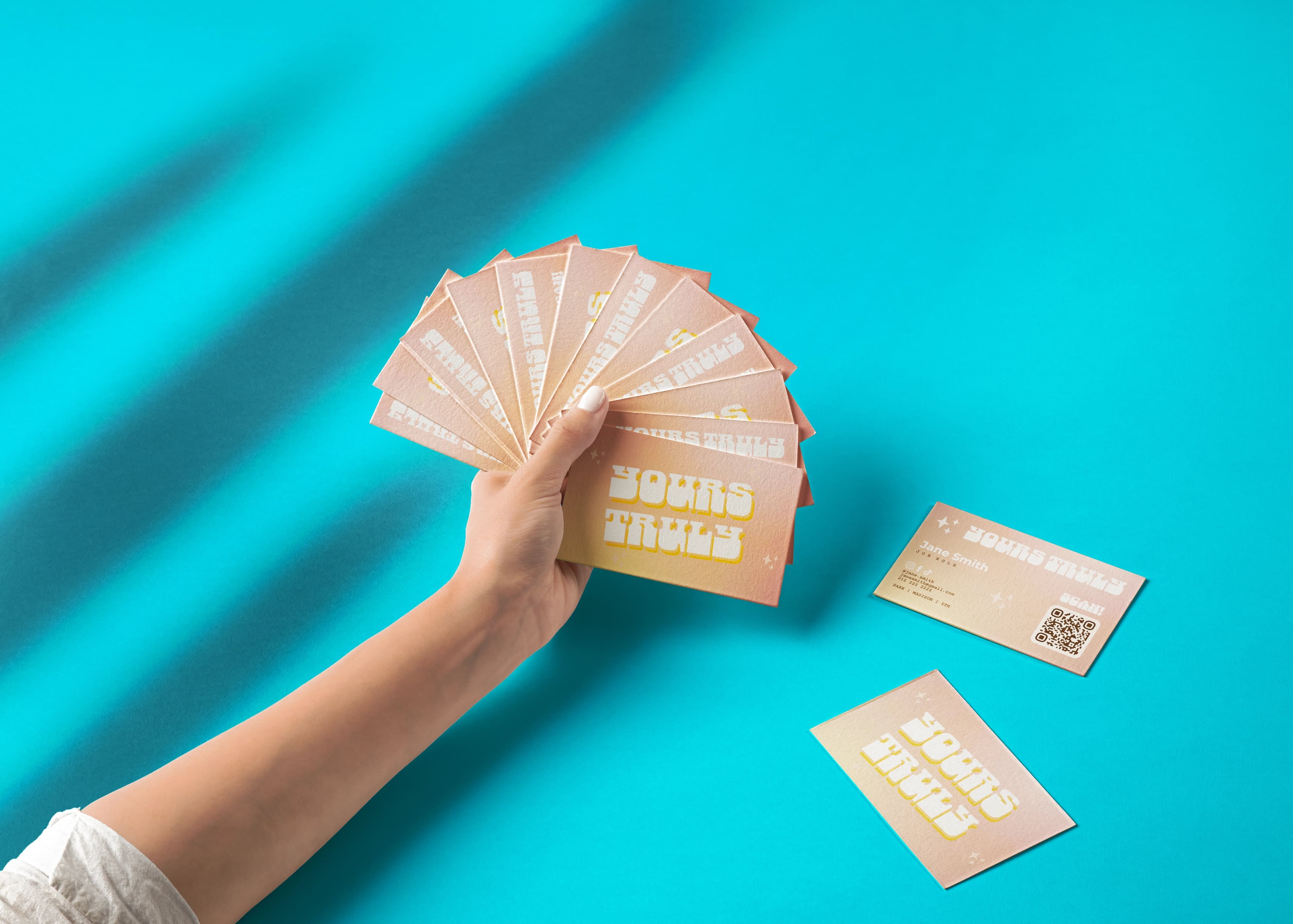 A hand presenting a fan of Ink business cards